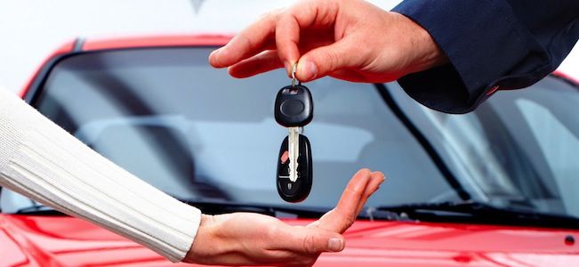 Imagen de una persona sosteniendo las llaves de un coche mientras mira hacia una sucursal de Ibancar. La imagen representa los problemas que pueden surgir al obtener un préstamo con aval de coche y la necesidad de presentar una reclamación contra esta empresa en caso de ser necesario.